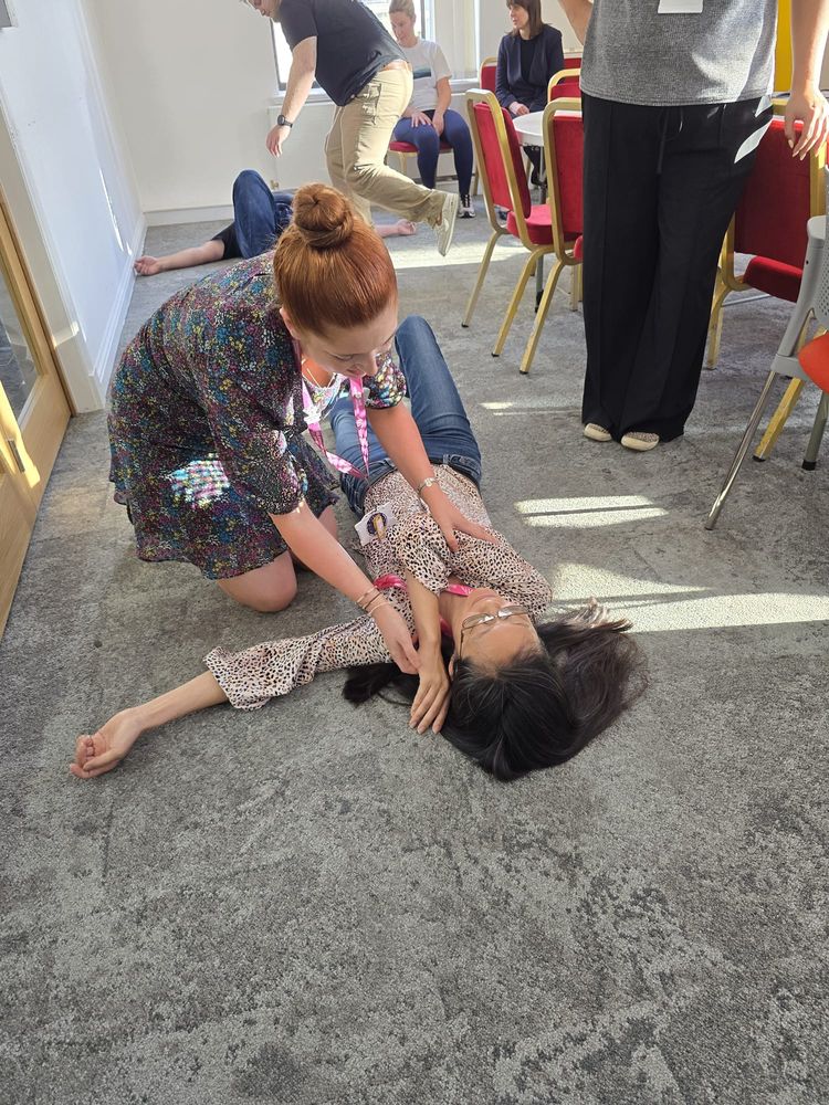 Delegates practising the recovery position during on-site first aid training