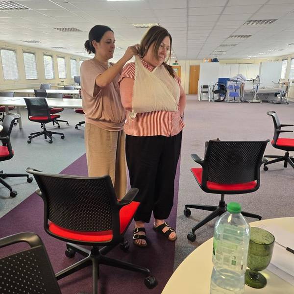 Applying an arm sling during first aid bandaging training